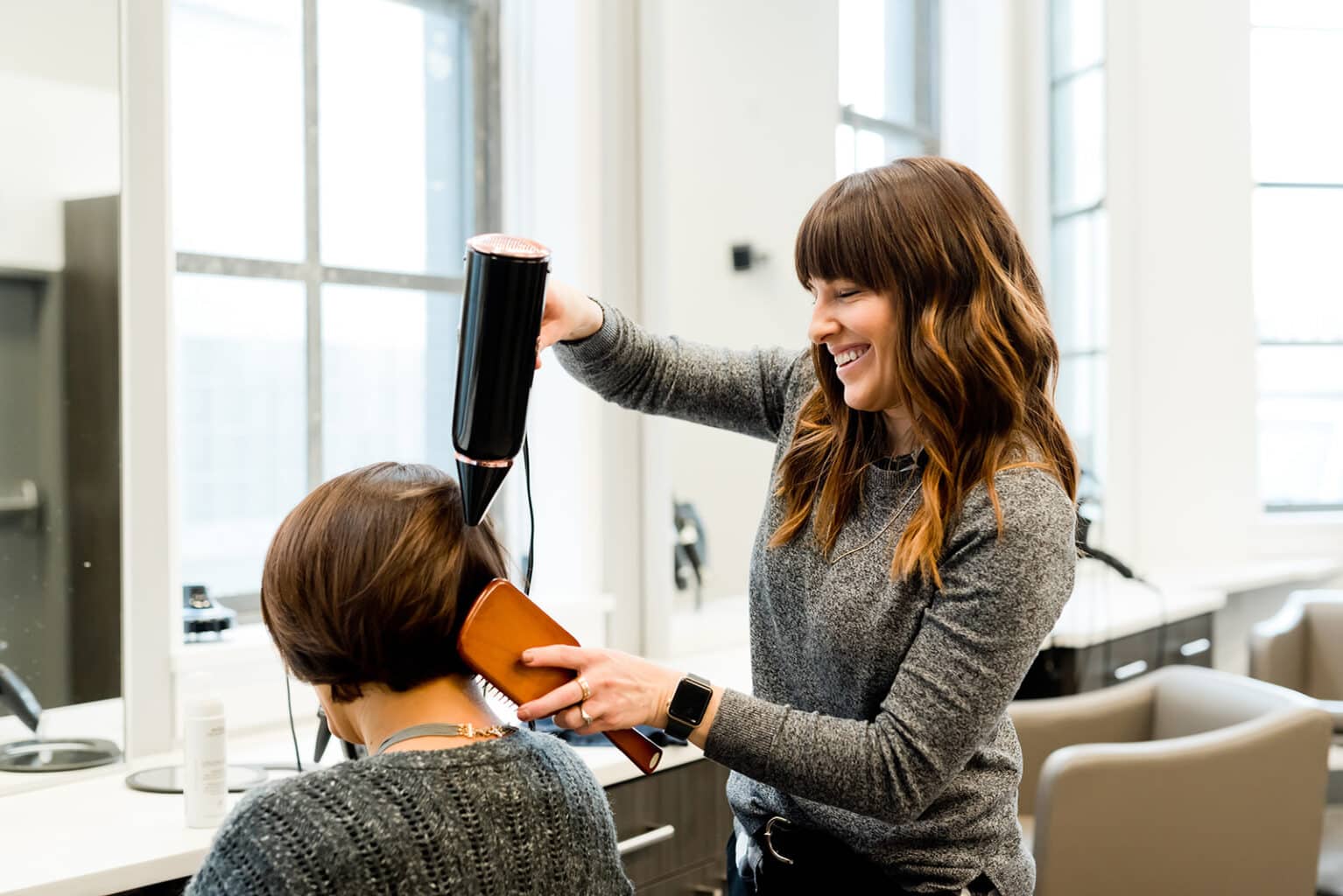 Friseurin föhnt das Haar einer Kundin bei einer Business Fotoreportage